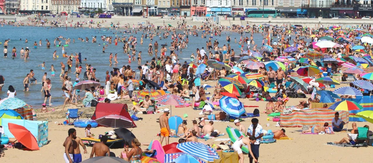 En strand tettpakket med mennesker på en varm sommerdag. Fotografi