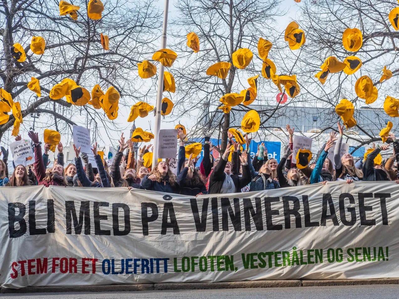 Mange ungdommer står bak et kjempestort banner hvor det står "Bli med på vinnerlaget. Stem for et oljefritt Lofoten, Vesterålen og Senja". Alle har de hver sin gule sydvest som de kaster opp i lufta i jubel.