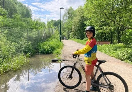 Gutt på sykkel ved siden av en dam. Fotografi.