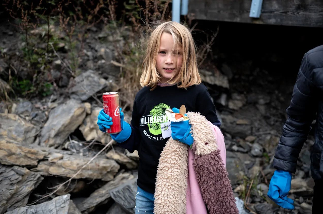 Jente med Miljøagentene-genser holder en brusboks og diverse søppel